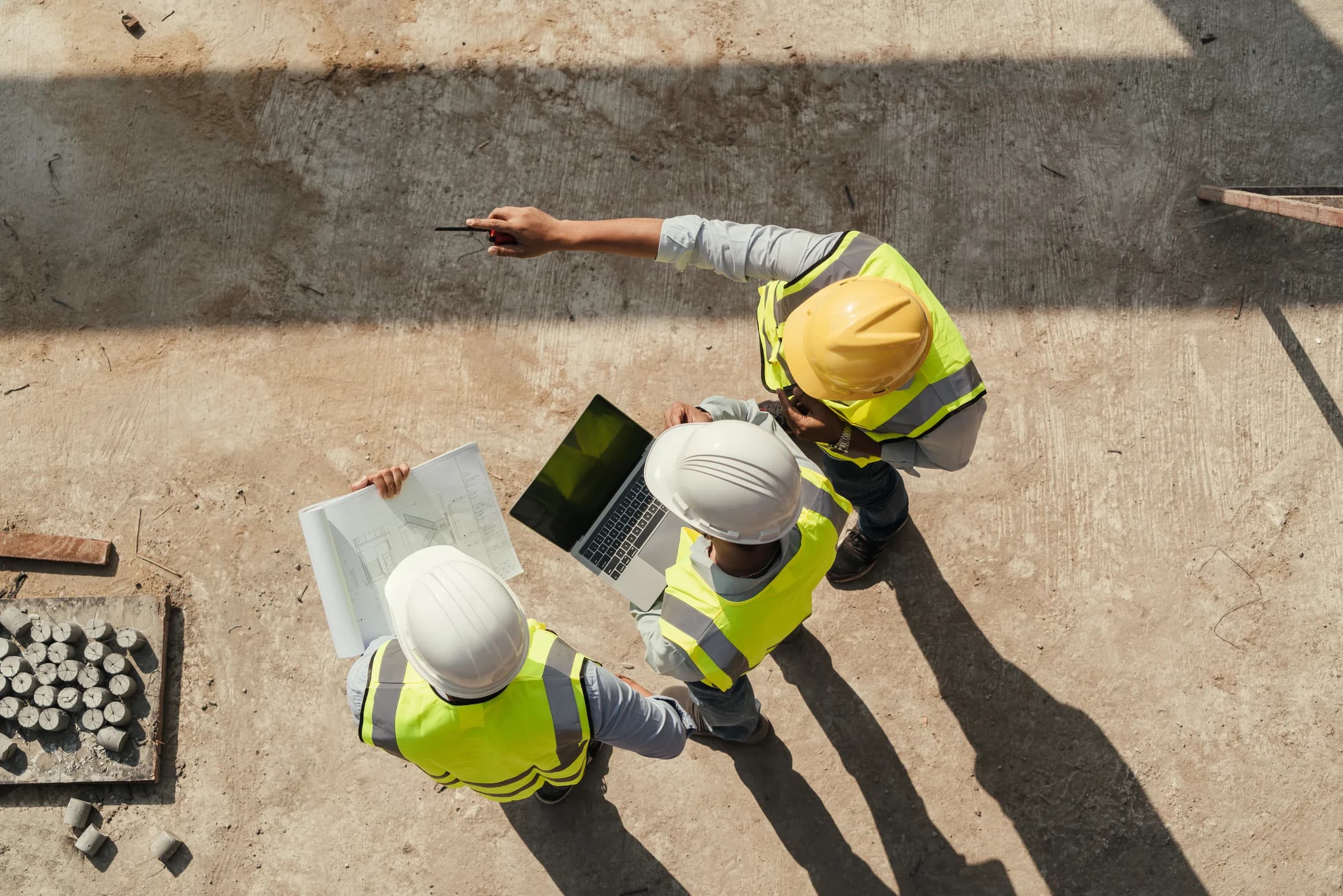 Construction team in hard hats and high-visibility clothing reviewing plans on site.
